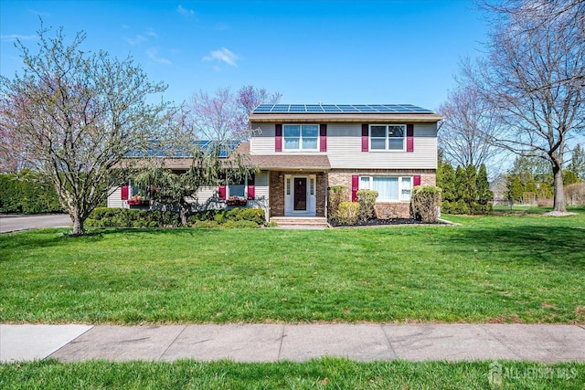view of front of property featuring roof mounted solar panels, brick siding, and a front lawn