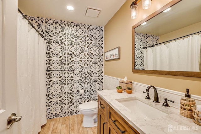full bathroom with visible vents, toilet, wainscoting, wood finished floors, and vanity