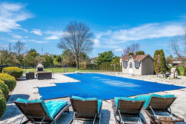 view of swimming pool with a fenced in pool, fence, an outdoor structure, a patio, and a fireplace