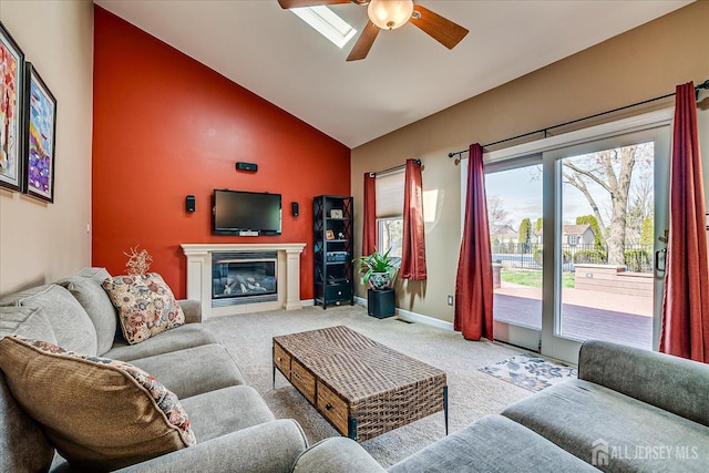 living room with baseboards, ceiling fan, carpet floors, high vaulted ceiling, and a glass covered fireplace