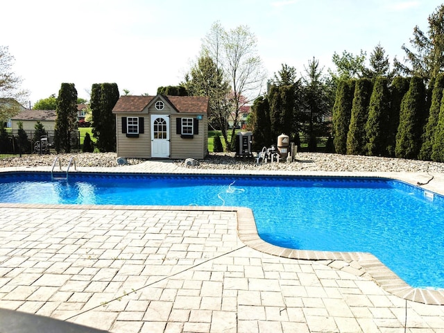 view of pool with fence, a fenced in pool, an outdoor structure, and a patio