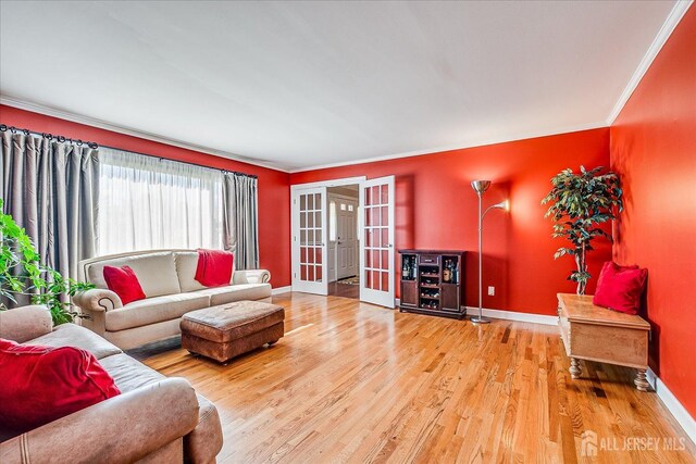 living area featuring wood finished floors, crown molding, baseboards, and french doors