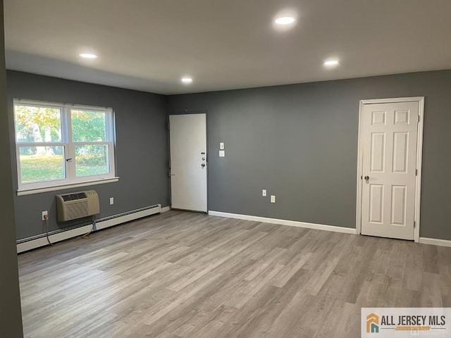 unfurnished room with a baseboard heating unit, recessed lighting, light wood-style flooring, and baseboards