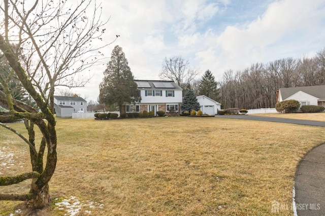 view of front of property with roof mounted solar panels, a front lawn, a garage, and fence