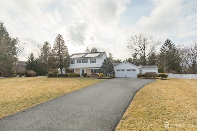 view of front facade with a detached garage, an outdoor structure, a front yard, and fence