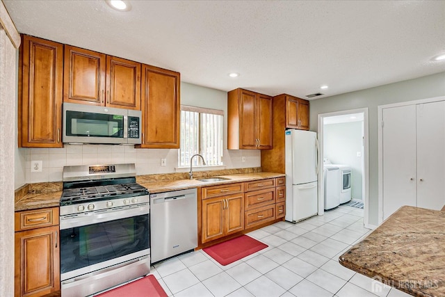68 Kelly Dr, Edison, NJ 08820 - kitchen with appliances with stainless steel finishes, brown cabinets, washing machine and clothes dryer, recessed lighting, and tasteful backsplash