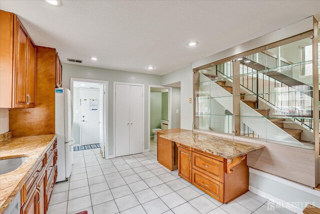 68 Kelly Dr, Edison, NJ 08820 - kitchen featuring brown cabinets, freestanding refrigerator, light stone countertops, recessed lighting, and light tile patterned floors