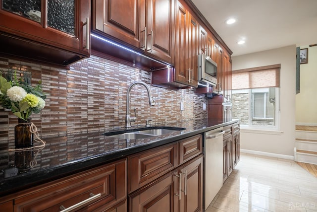 kitchen with sink, decorative backsplash, dark stone countertops, and appliances with stainless steel finishes