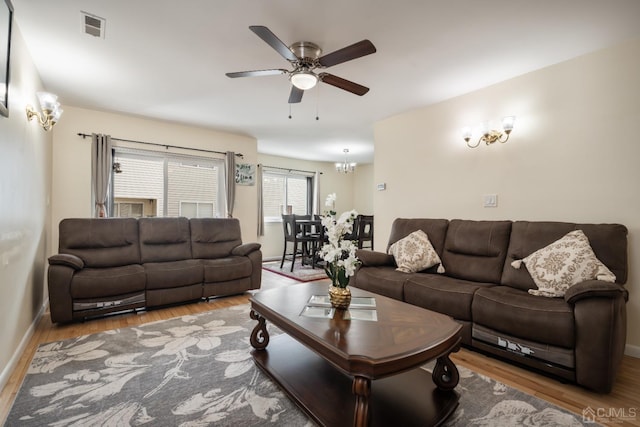 living room featuring ceiling fan with notable chandelier and hardwood / wood-style flooring