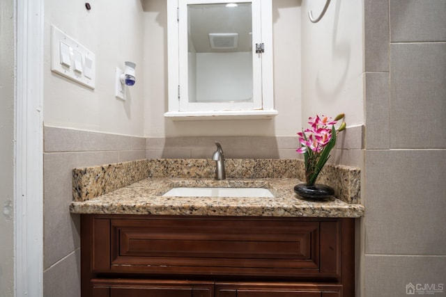 bathroom featuring vanity and tile walls