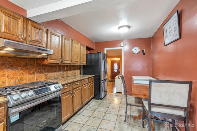 kitchen featuring light stone counters, appliances with stainless steel finishes, light tile patterned floors, and backsplash