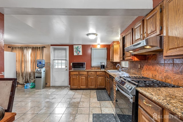 kitchen with tasteful backsplash, sink, light stone countertops, and appliances with stainless steel finishes