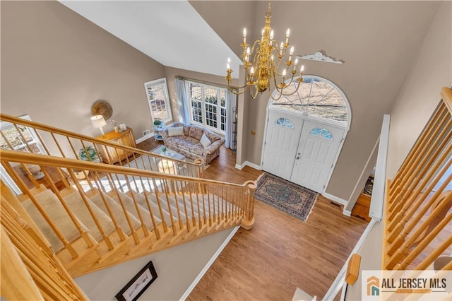 foyer featuring a notable chandelier, high vaulted ceiling, wood finished floors, and baseboards