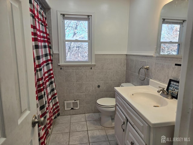 full bathroom featuring vanity, visible vents, wainscoting, tile patterned floors, and toilet