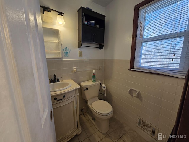 bathroom with tile walls, vanity, toilet, and tile patterned floors