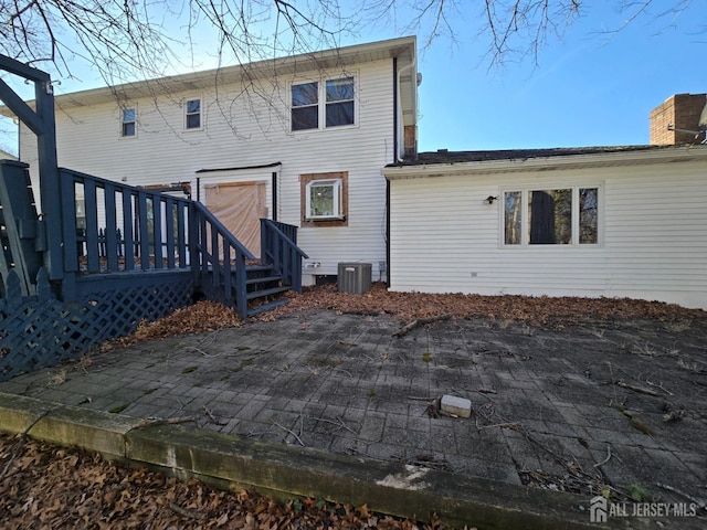 back of house featuring central air condition unit, a patio, and a chimney