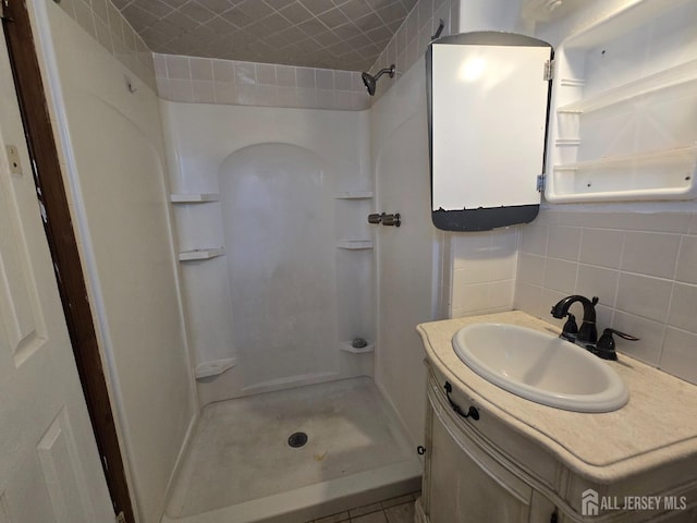 bathroom with tile walls, tasteful backsplash, a shower, and vanity