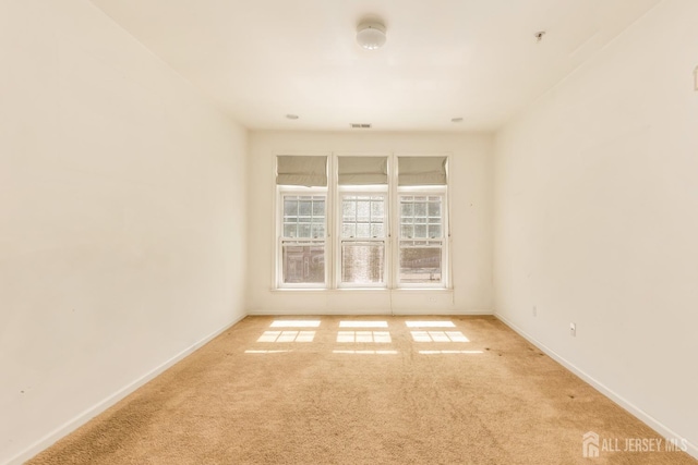 carpeted spare room featuring visible vents and baseboards