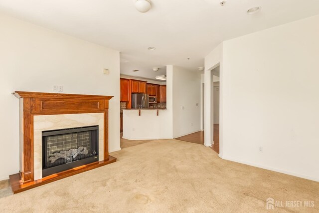 unfurnished living room with recessed lighting, a high end fireplace, and light colored carpet