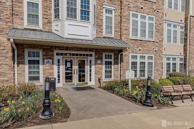 property entrance featuring french doors, stone siding, metal roof, and a standing seam roof
