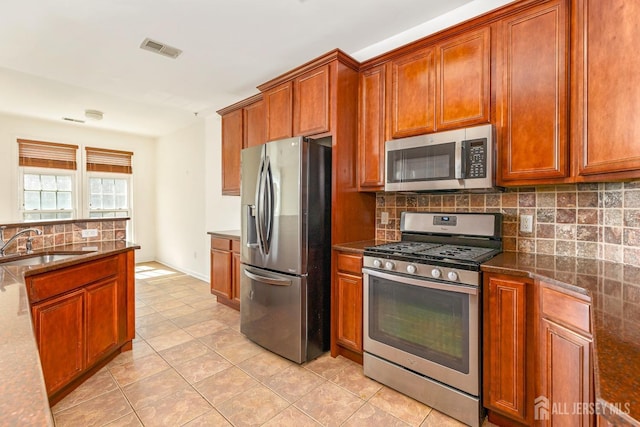 kitchen with visible vents, a sink, stainless steel appliances, backsplash, and light tile patterned flooring