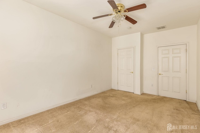 empty room with light carpet, ceiling fan, baseboards, and visible vents