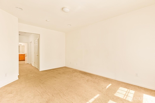 unfurnished room with baseboards and light colored carpet