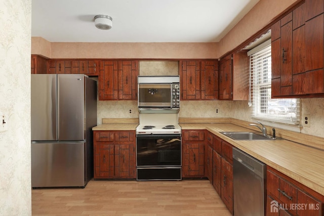 kitchen with stainless steel appliances, sink, and light hardwood / wood-style flooring