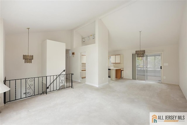unfurnished room featuring high vaulted ceiling, light carpet, baseboards, and a notable chandelier