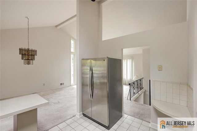 kitchen featuring freestanding refrigerator, light tile patterned floors, high vaulted ceiling, light carpet, and beam ceiling