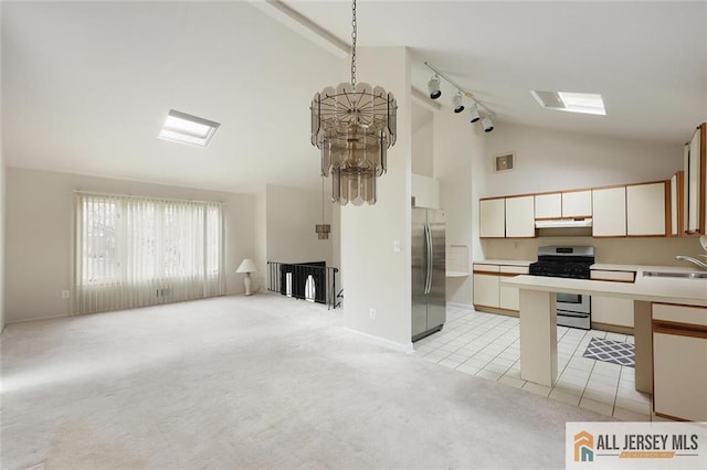 kitchen featuring track lighting, open floor plan, light colored carpet, a sink, and appliances with stainless steel finishes