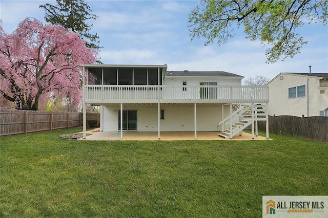 rear view of house featuring a yard, a patio area, a sunroom, a deck, and a fenced backyard