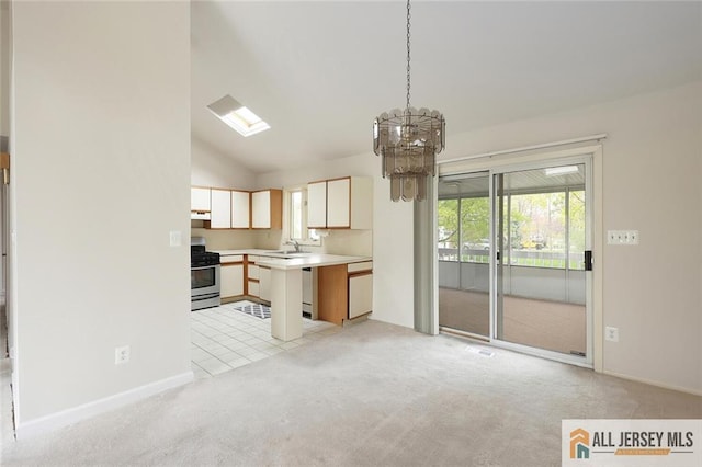 kitchen featuring stainless steel gas range, a chandelier, vaulted ceiling, light countertops, and light colored carpet