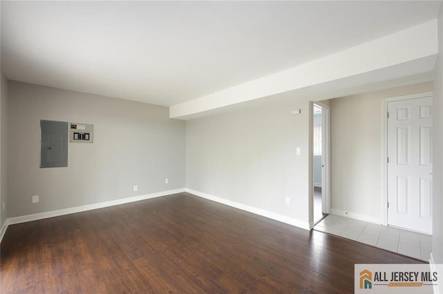 spare room featuring baseboards, electric panel, and wood finished floors