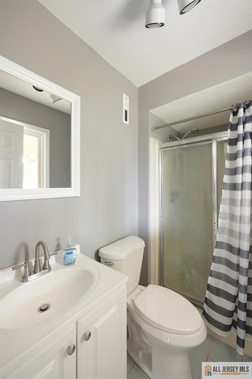 full bath with vanity, toilet, tile patterned floors, and a stall shower