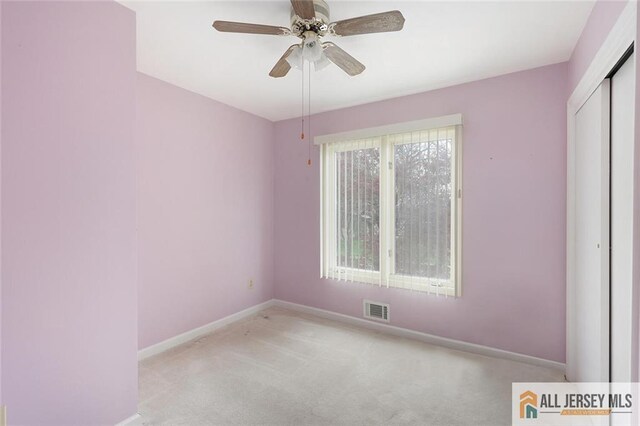 unfurnished bedroom featuring a closet, carpet, baseboards, ceiling fan, and visible vents