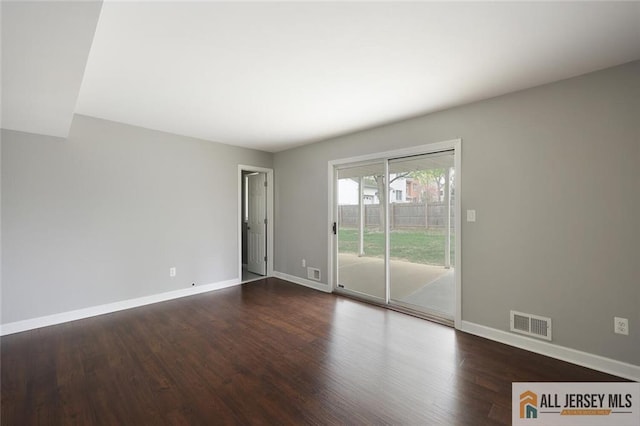spare room with baseboards, visible vents, and dark wood-type flooring