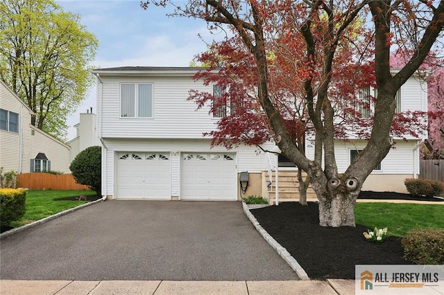 view of front of house with a garage, fence, a front lawn, and aphalt driveway