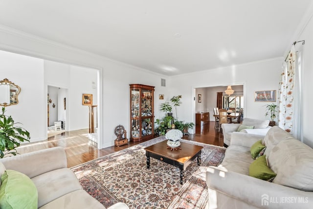 living area with baseboards, wood finished floors, and crown molding