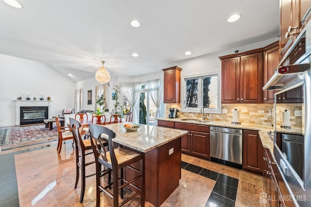 kitchen featuring dishwasher, a glass covered fireplace, a breakfast bar area, a sink, and recessed lighting