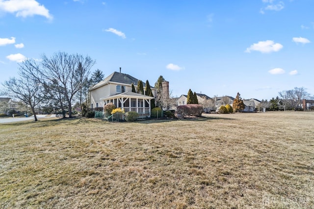 rear view of property with a sunroom and a lawn