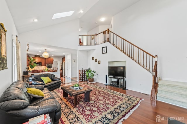 living area featuring a skylight, visible vents, baseboards, stairway, and wood finished floors