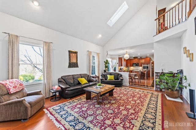 living area featuring high vaulted ceiling, a skylight, wood finished floors, and recessed lighting