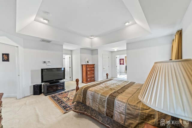 carpeted bedroom featuring visible vents, a tray ceiling, and baseboards