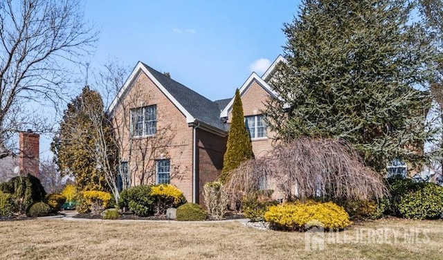 view of side of home with brick siding and a lawn