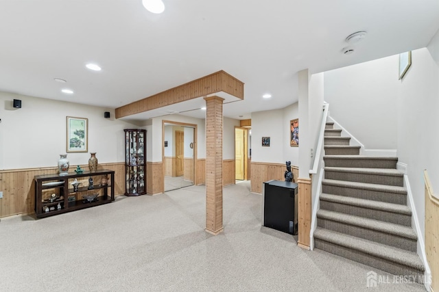 basement with stairway, recessed lighting, wainscoting, and wooden walls