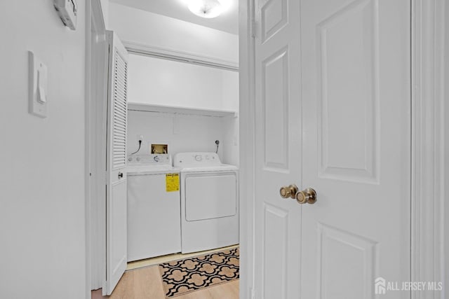 clothes washing area with light wood-type flooring, laundry area, and washer and clothes dryer