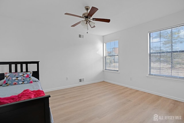 bedroom with light wood-type flooring, baseboards, visible vents, and ceiling fan