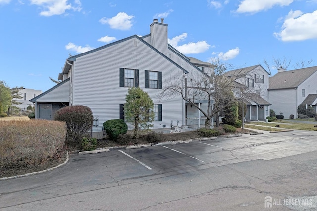 view of side of property with uncovered parking and a chimney