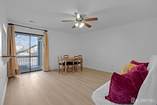 dining space with a ceiling fan, visible vents, baseboards, and wood finished floors